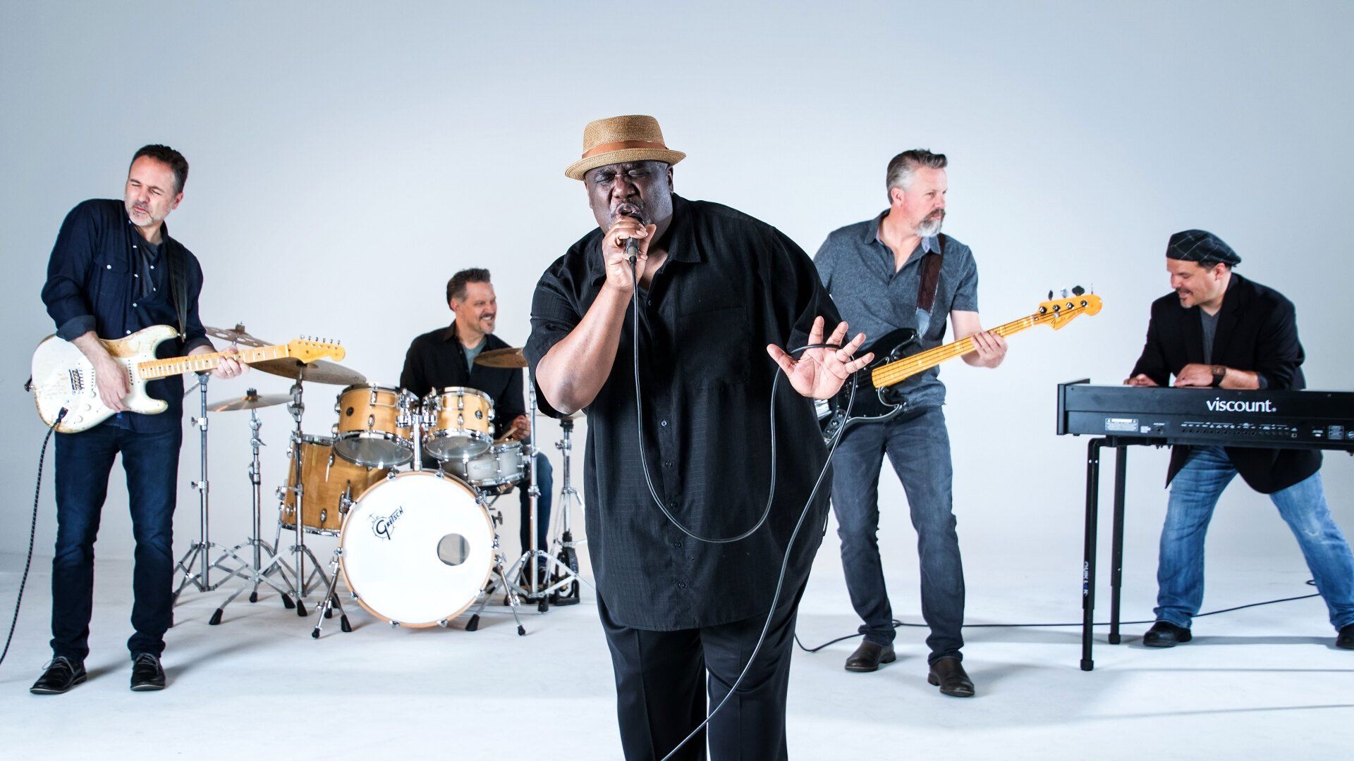 A man is singing into a microphone in front of a band.