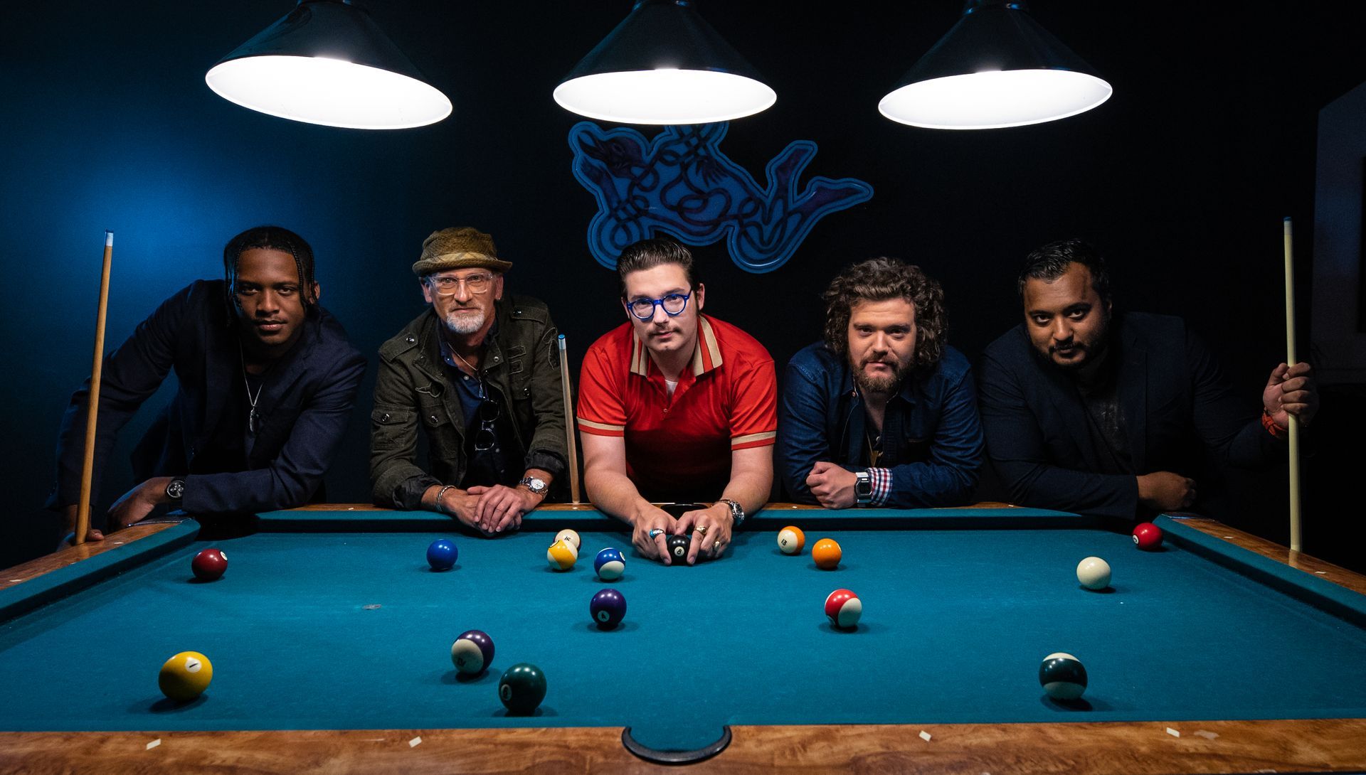 A group of men are standing around a pool table.