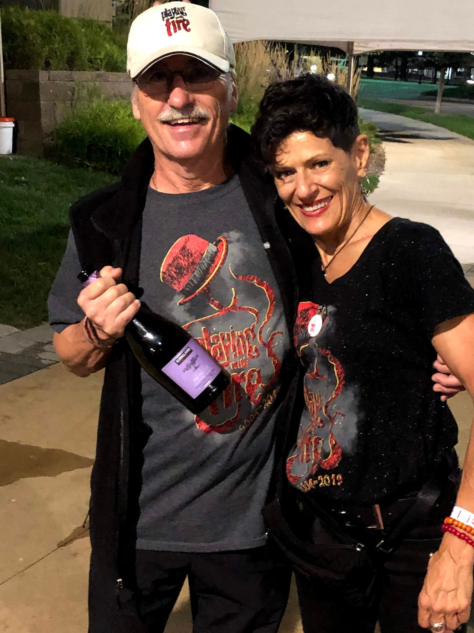 A man is holding a bottle of wine next to a woman