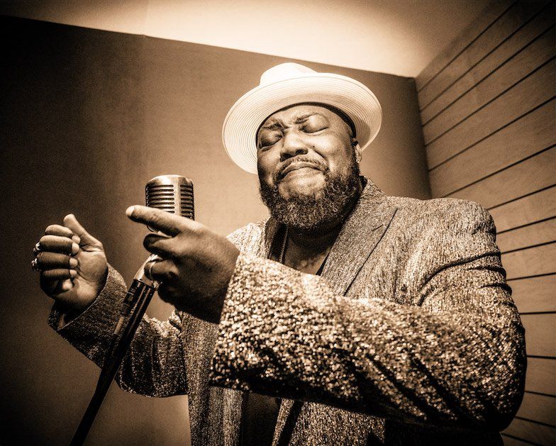 A man in a hat is singing into a microphone.