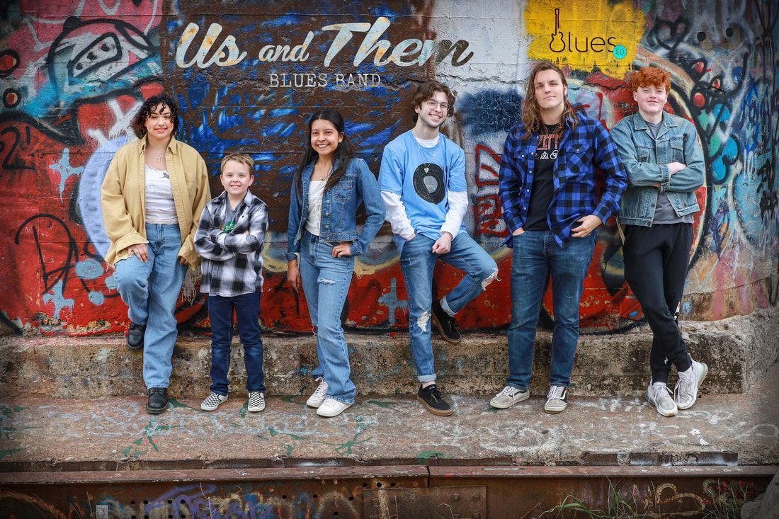 A group of people are standing in front of a graffiti covered wall.