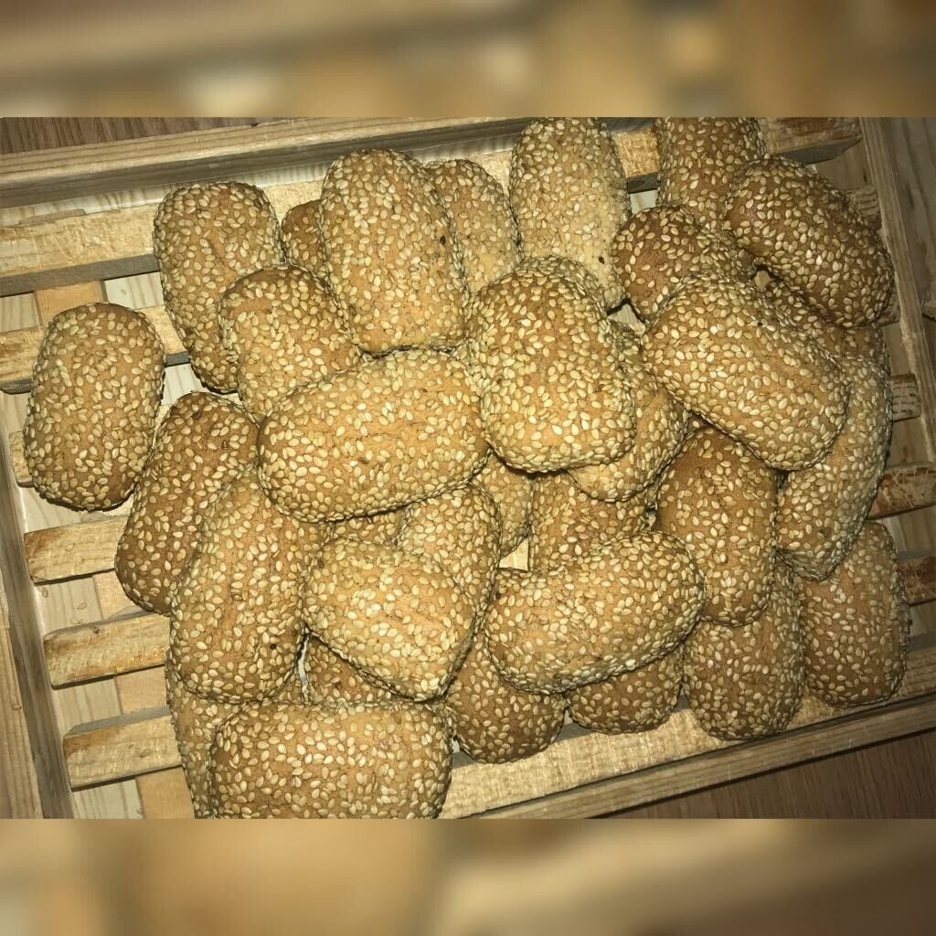 Tray of sesame-coated bread rolls in a basket, viewed from above.
