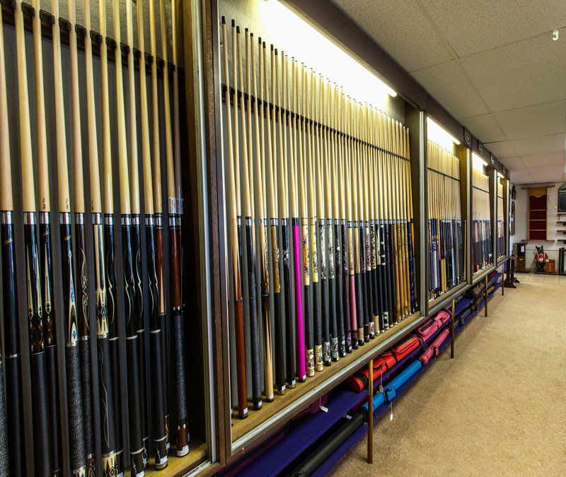 Rows of golf clubs displayed in a shop aisle, with a beige carpeted floor and bright overhead lighting