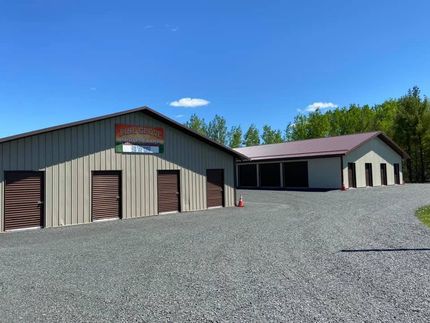 Tan metal storage building with multiple garage doors on a gravel lot under a blue sky