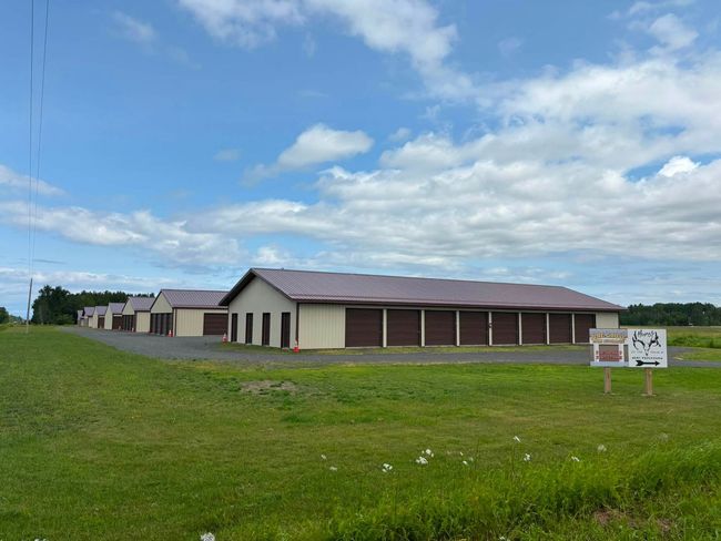 Single-story beige building with brown roof on a grassy field under a partly cloudy sky