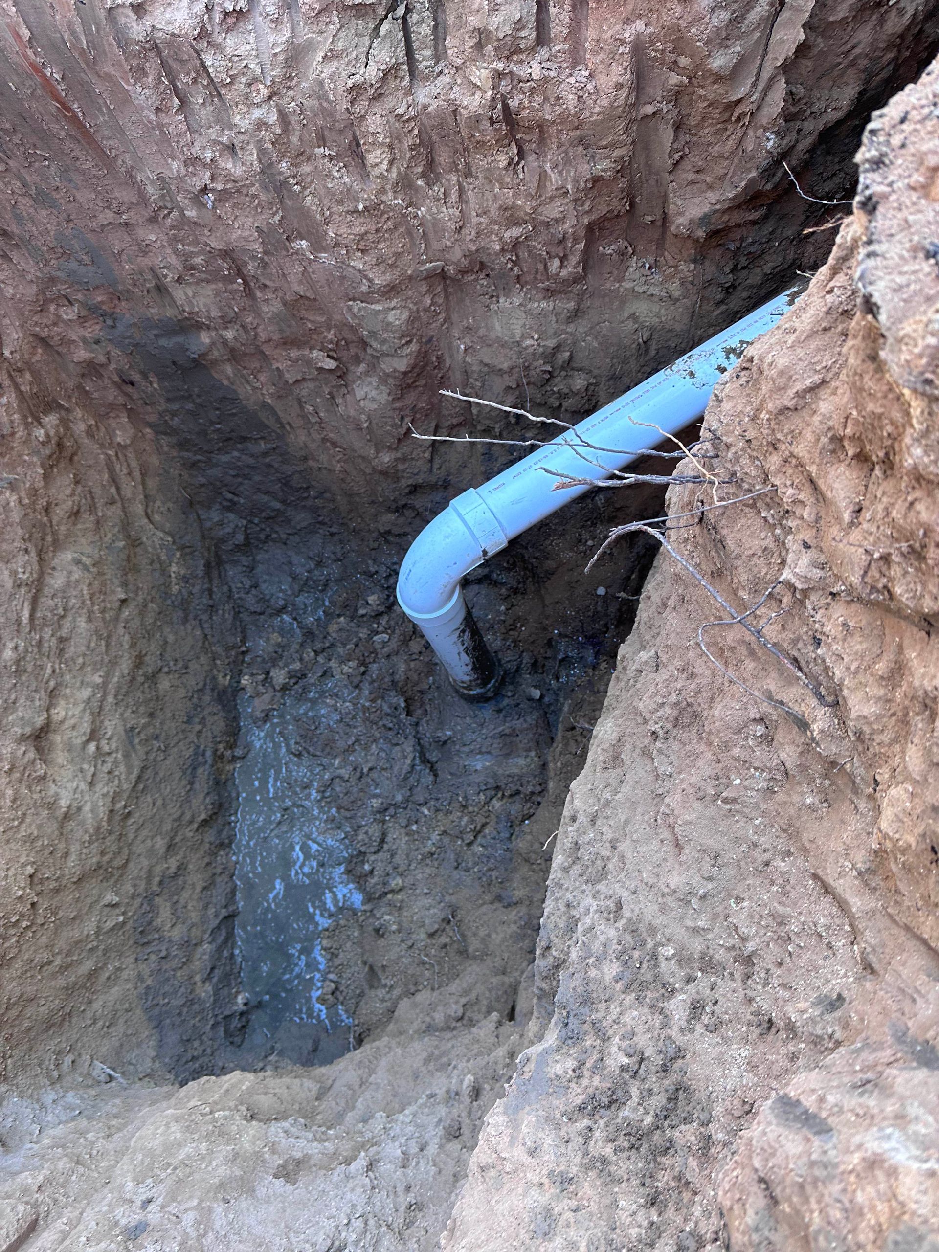 A blue pipe is coming out of a hole in the ground.