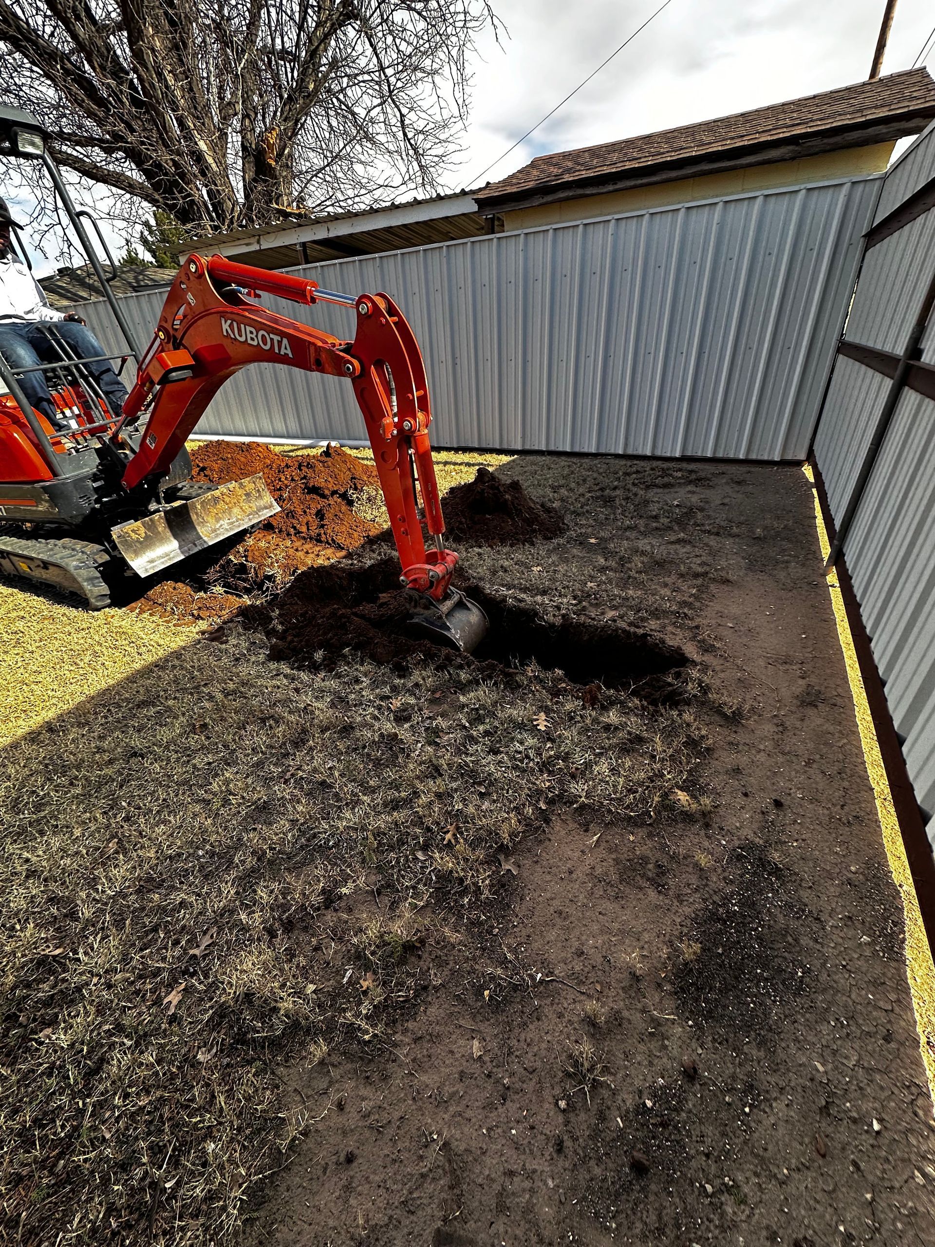 An orange excavator is digging a hole in the ground