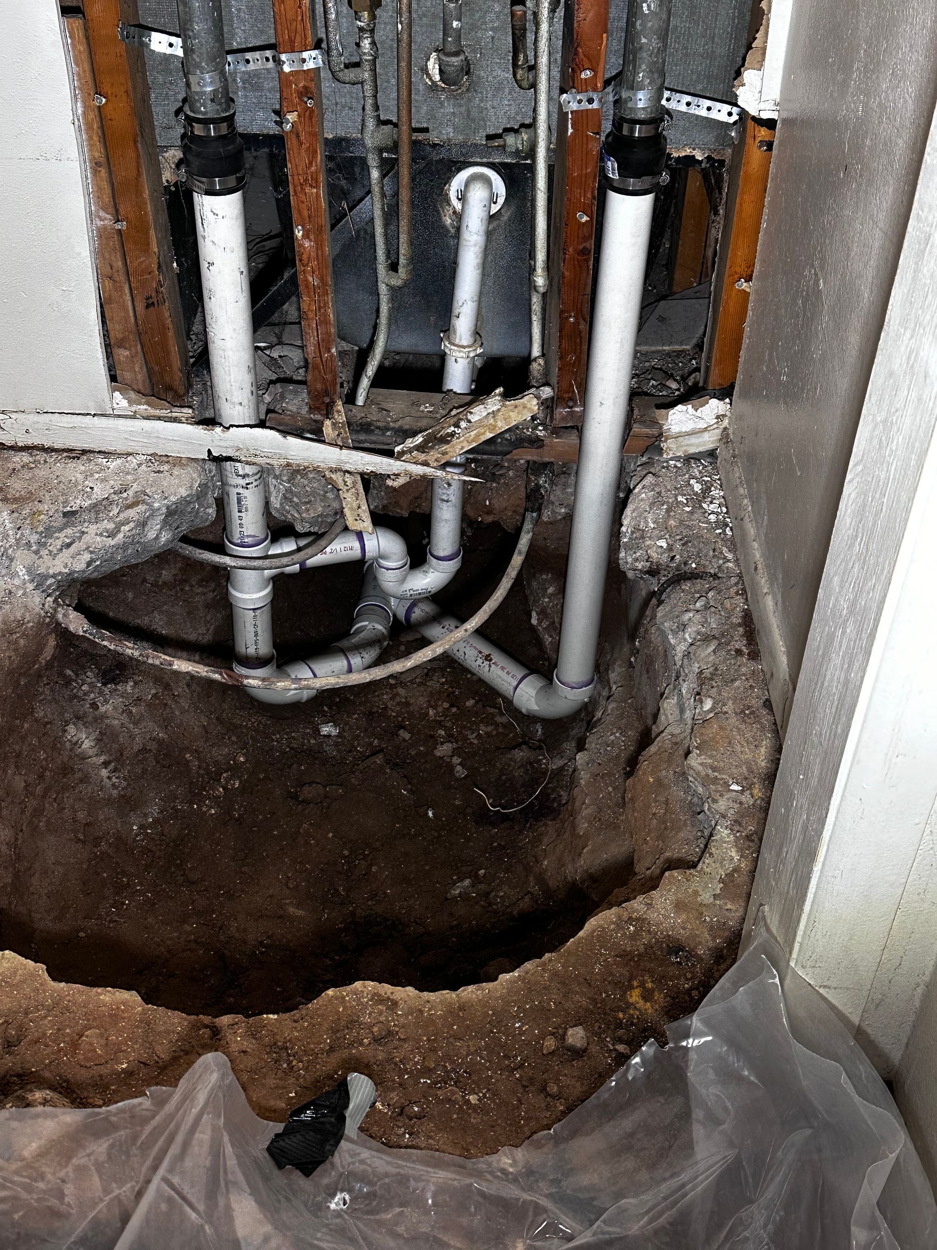 A hole in the ground with pipes coming out of it