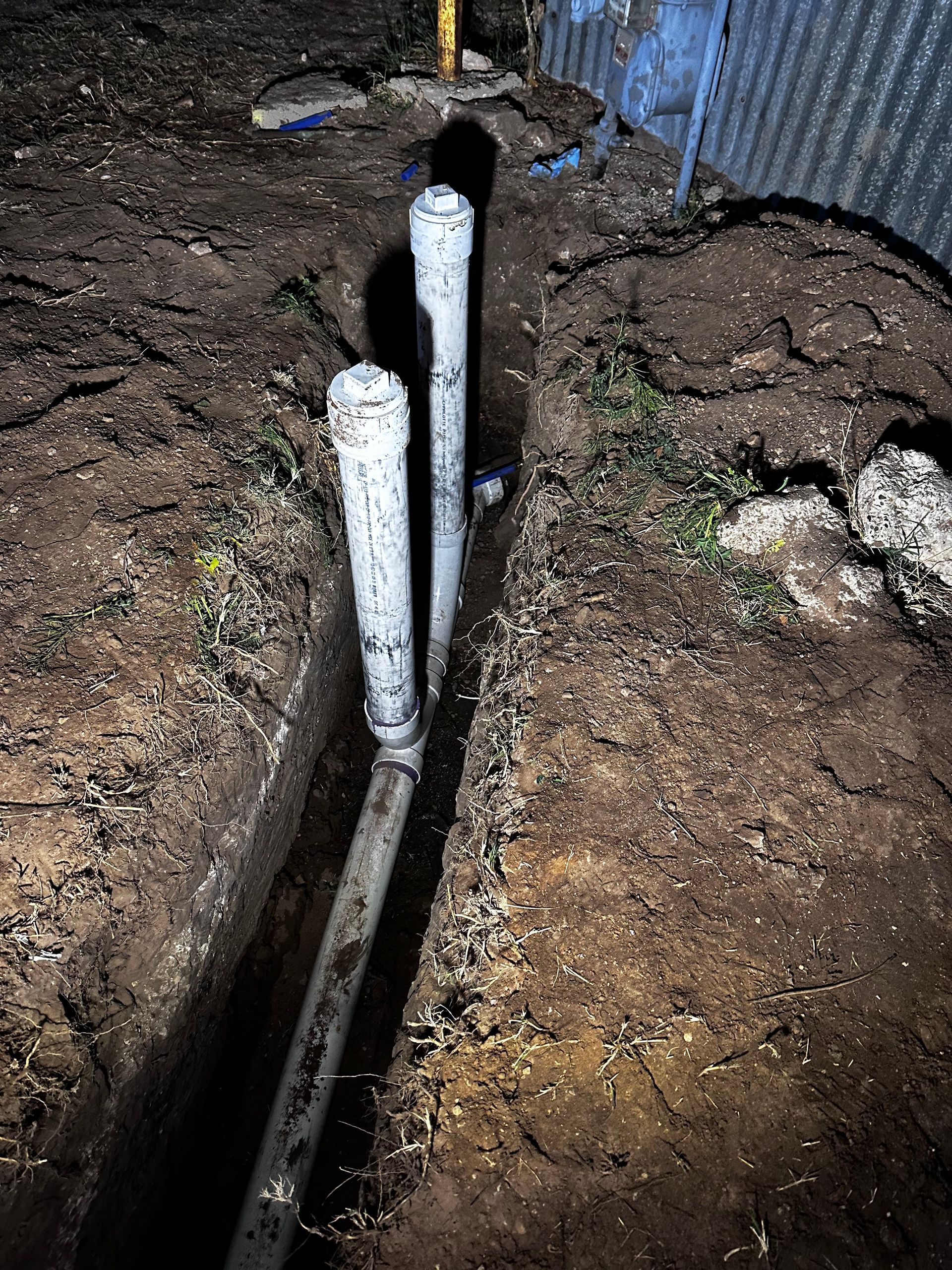 A couple of white pipes are laying in the dirt