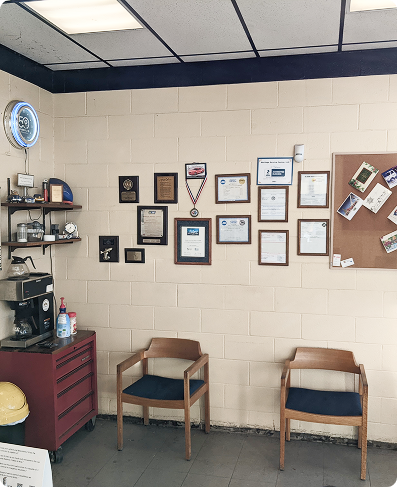 Office wall with framed certificates and awards above two chairs in a waiting area | Heritage Service Centre