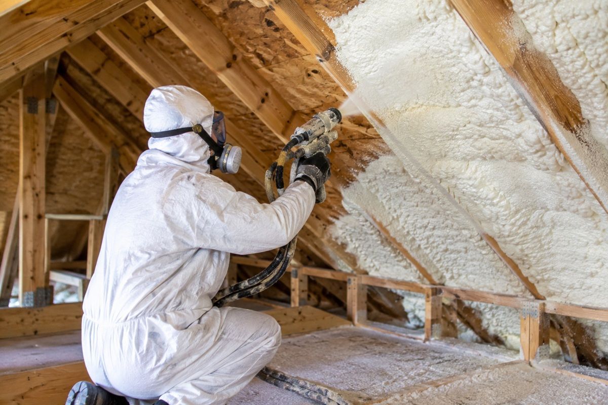  Contractor spraying foam insulation on attic roof rafters