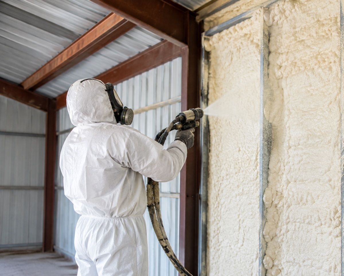 Contractor spraying foam insulation on a metal building wall