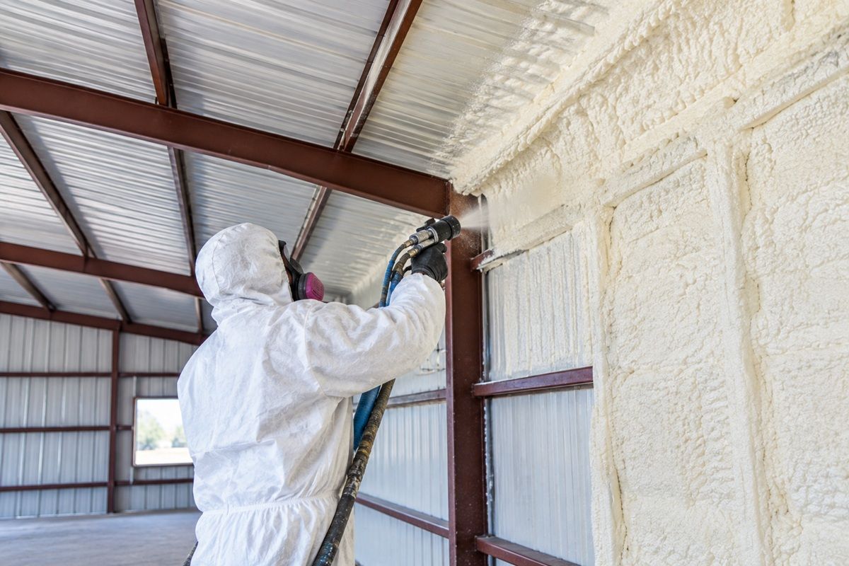 Contractor applying spray foam insulation inside a metal building in Mission TX.