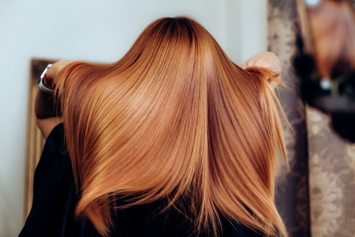 Una donna si spazzola i lunghi capelli rossi davanti allo specchio.