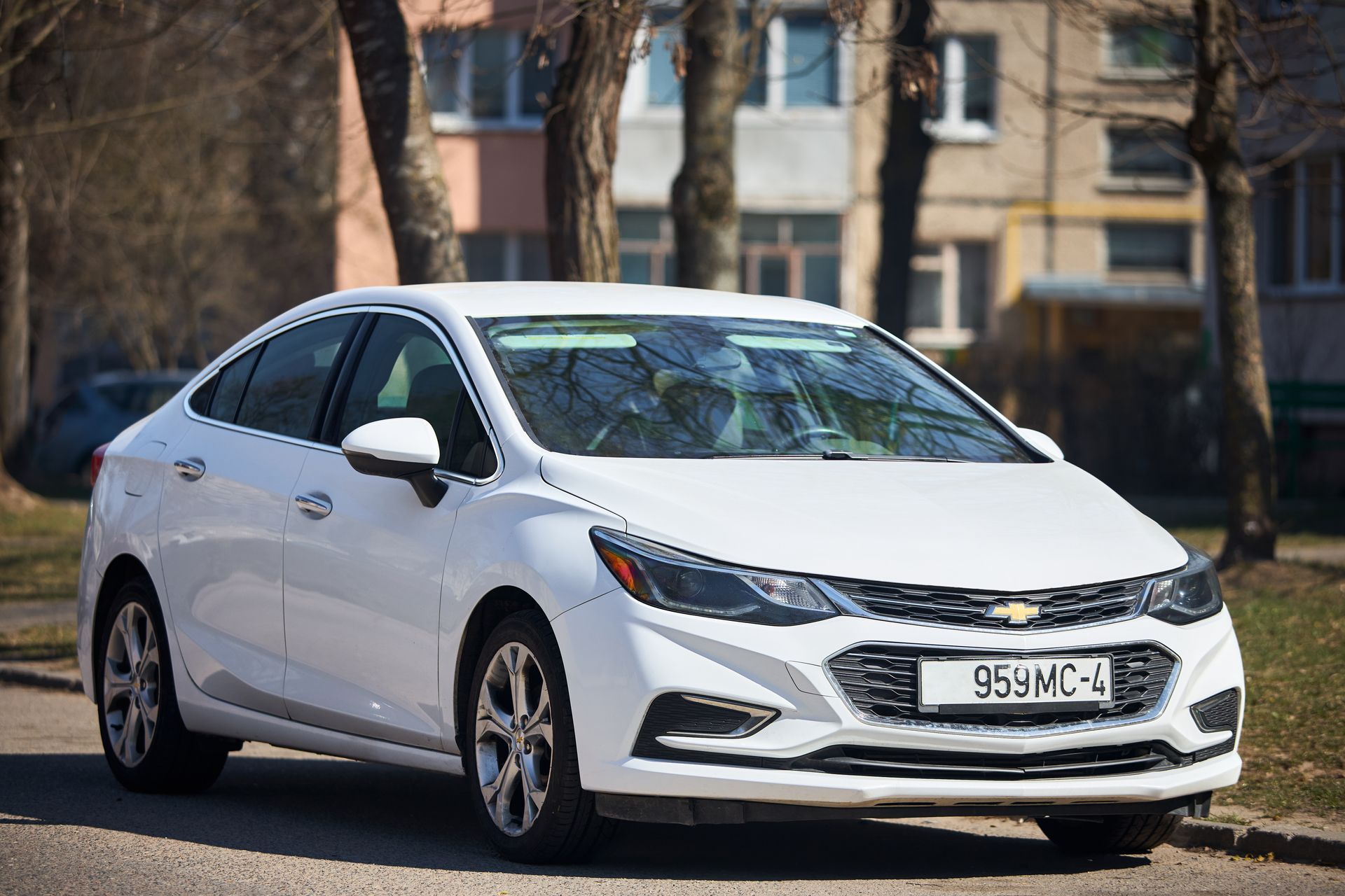 White Chevrolet Cruze sedan parked on a city street, daytime.