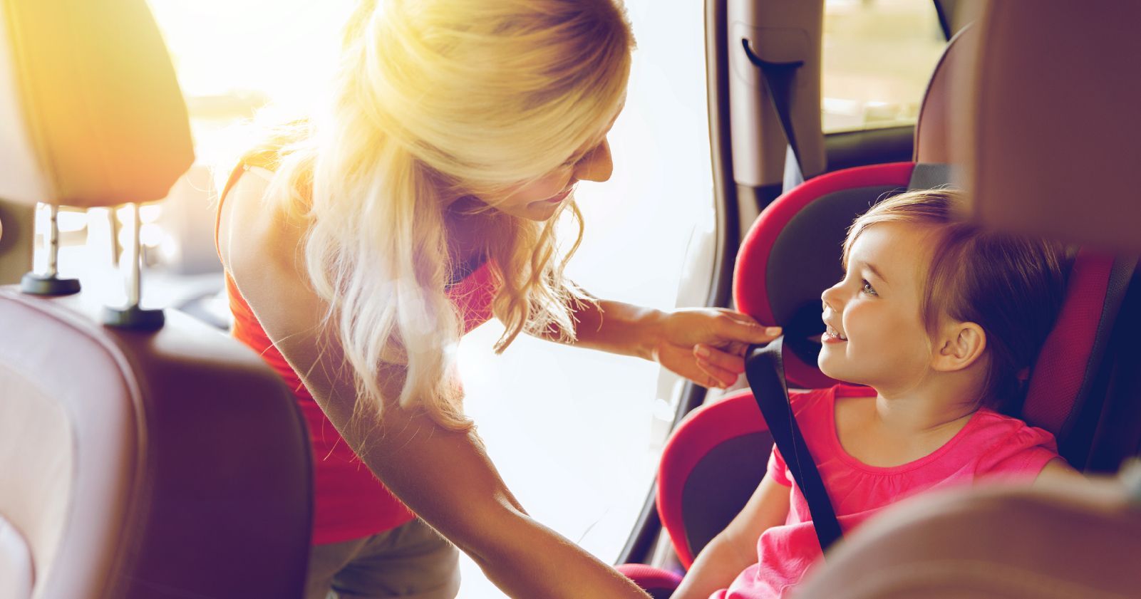a woman is putting a child in a car seat .
