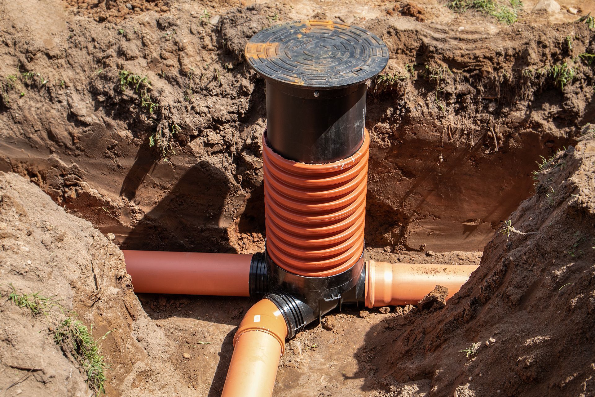 An inspection chamber installed in a trench, featuring a black riser.