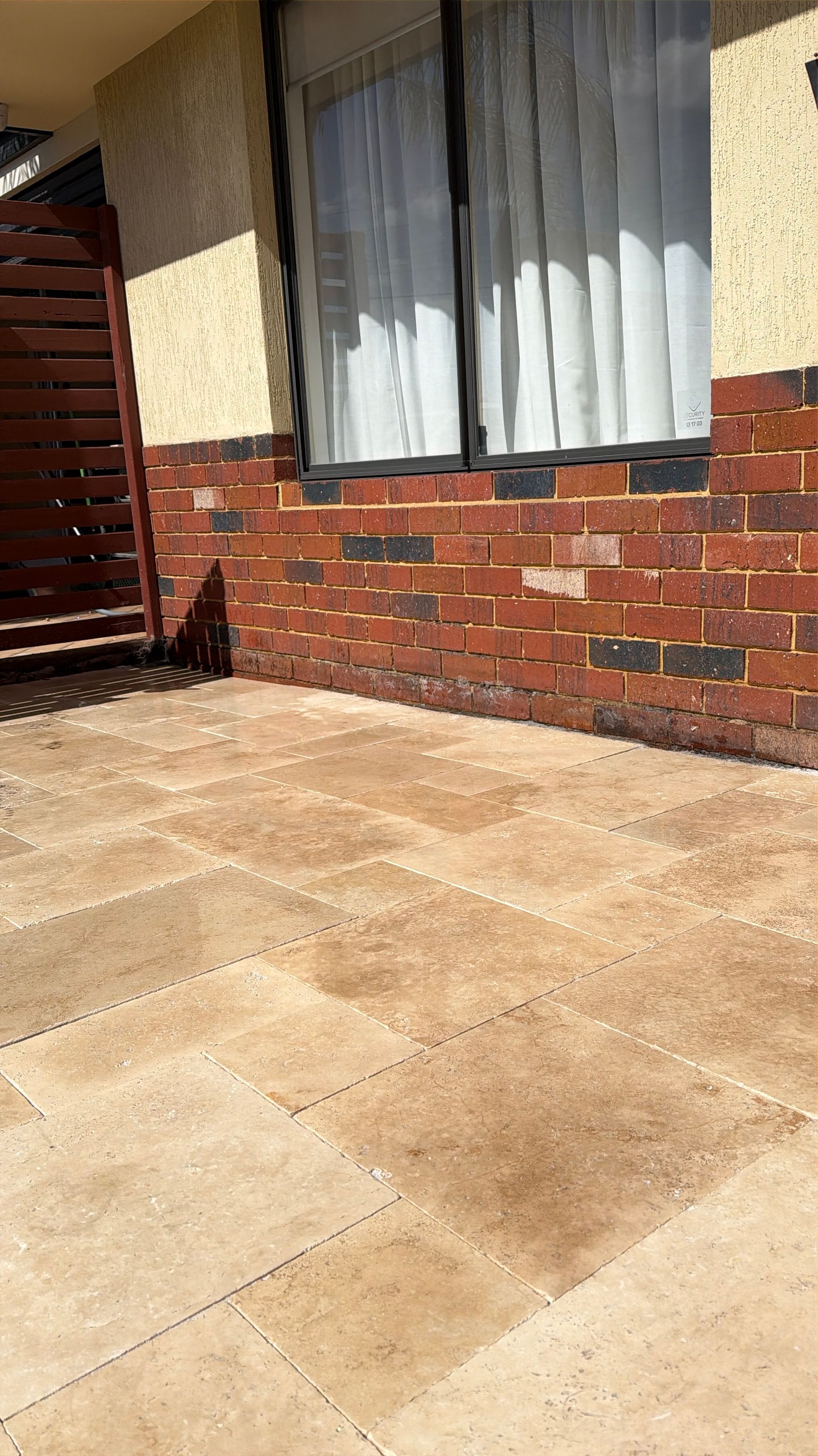 A close-up of a wall made of irregularly shaped, multi-toned gray and tan natural stones fitted together.