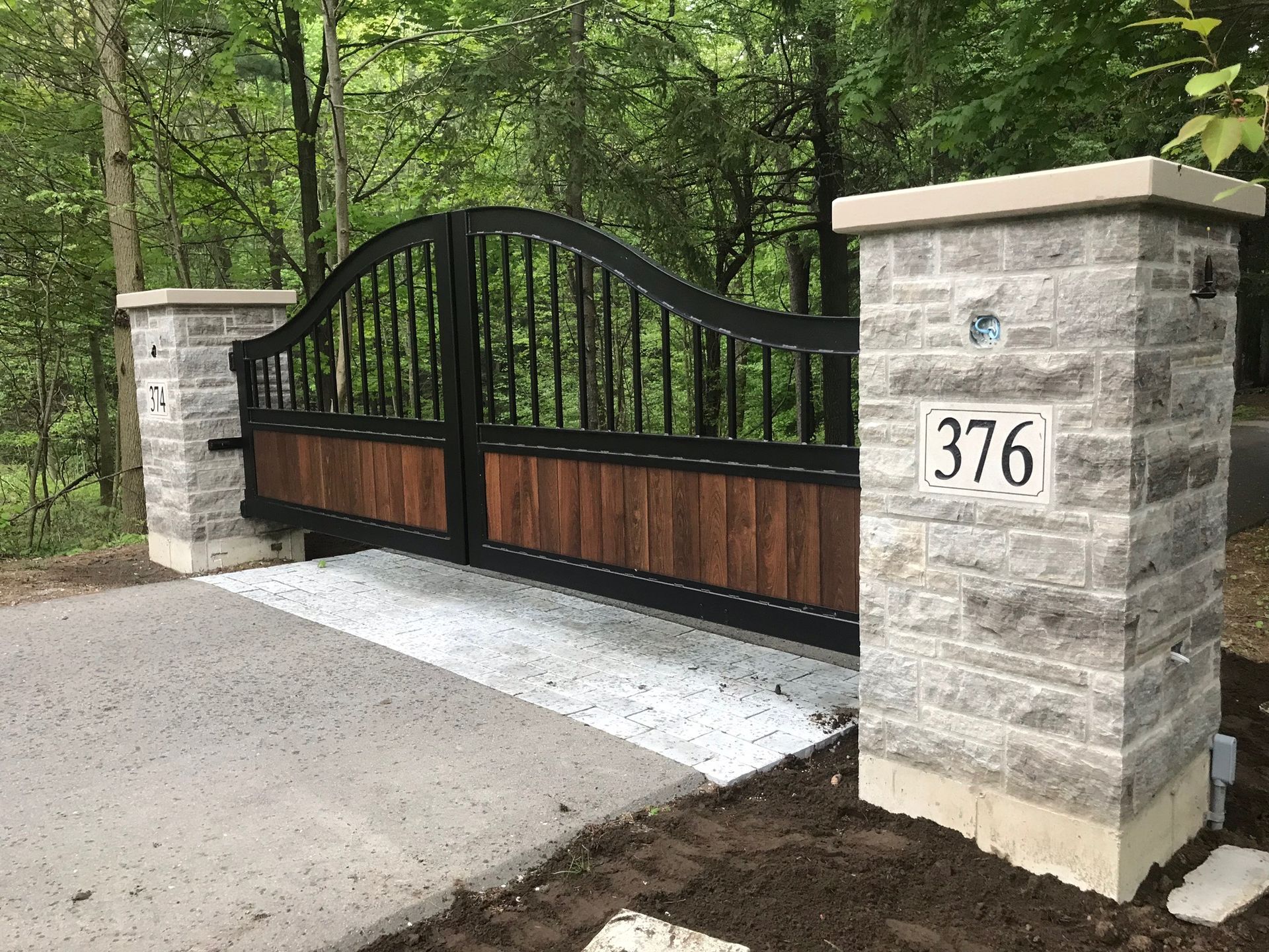Stone gate pillars with a black and wood gate, displaying the number 376.