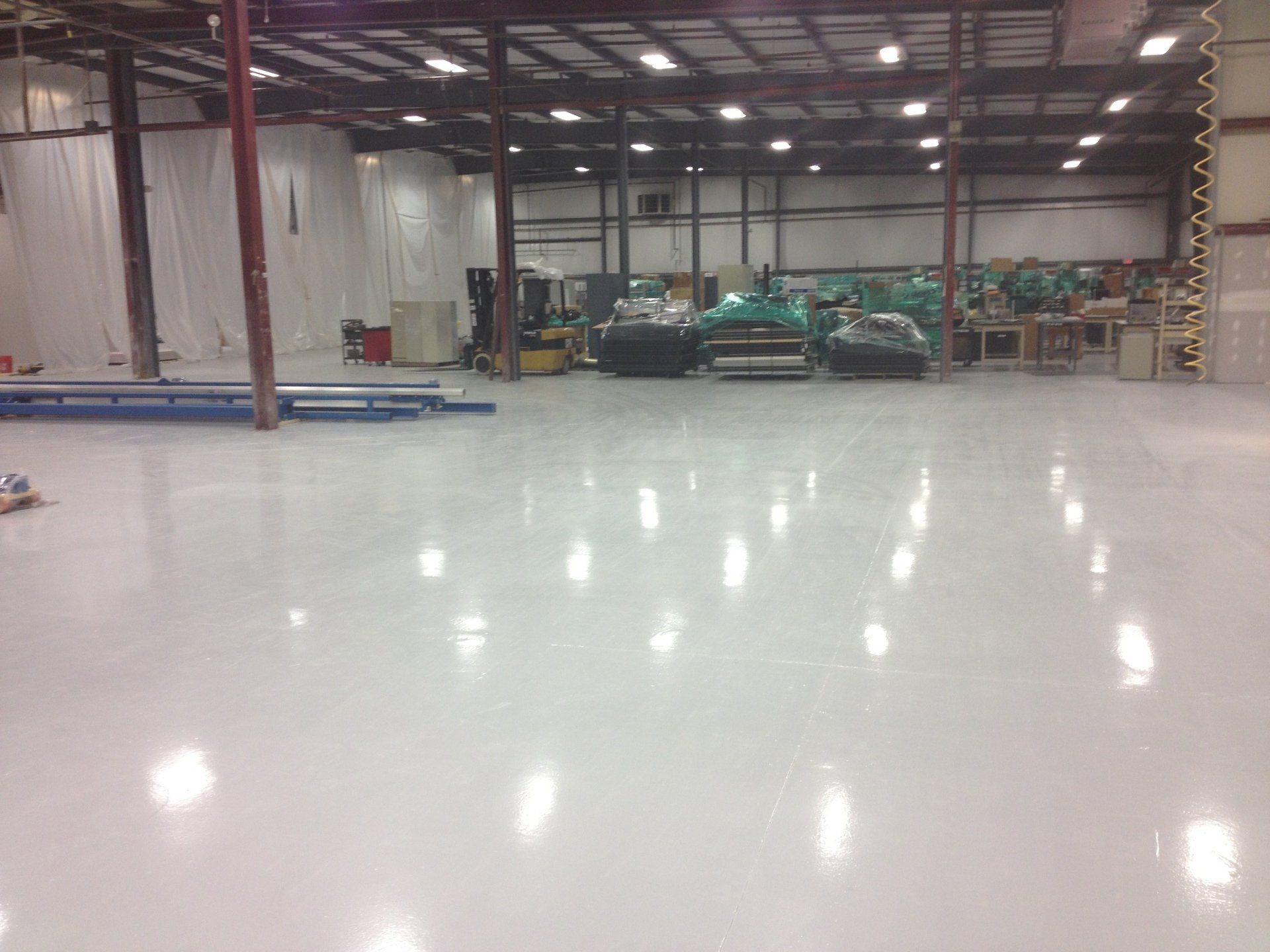 A large warehouse with a white floor and lots of machinery