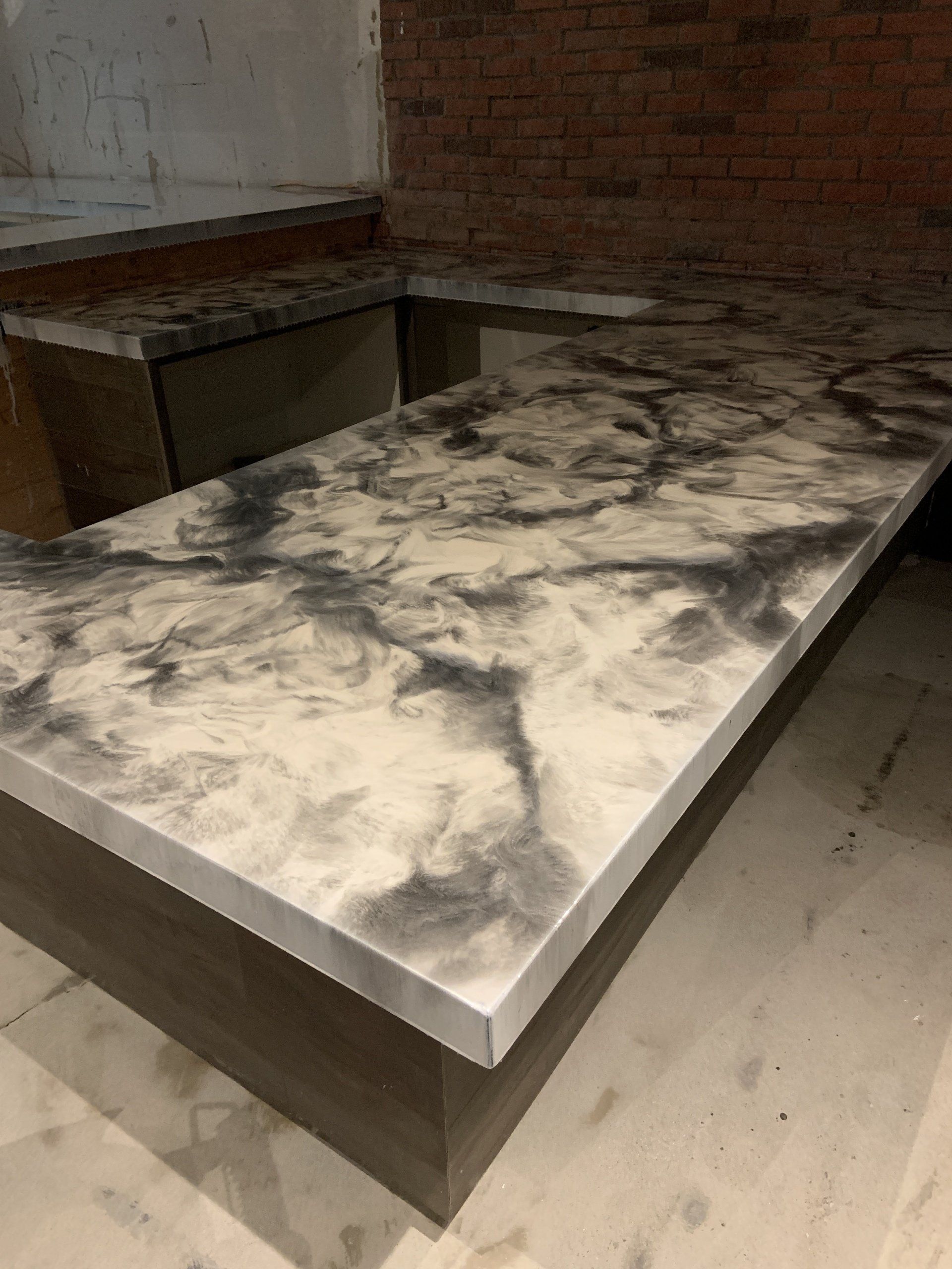 A table with a marble counter top in a room with a brick wall.