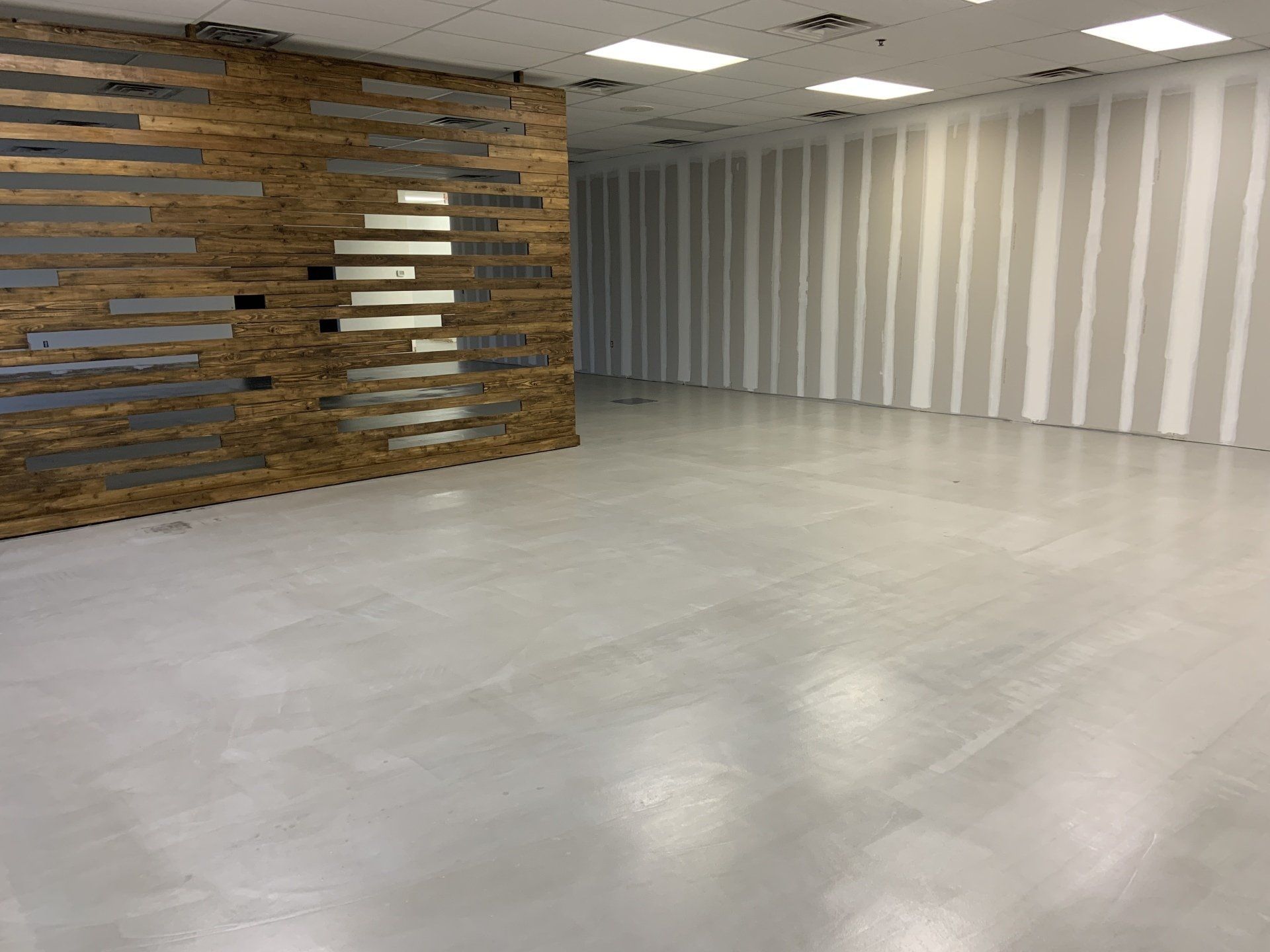 A large empty room with a wooden wall and a white floor.