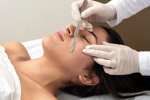 Cosmetic procedure on a woman’s face with gloved hands applying a fine tool near her nose