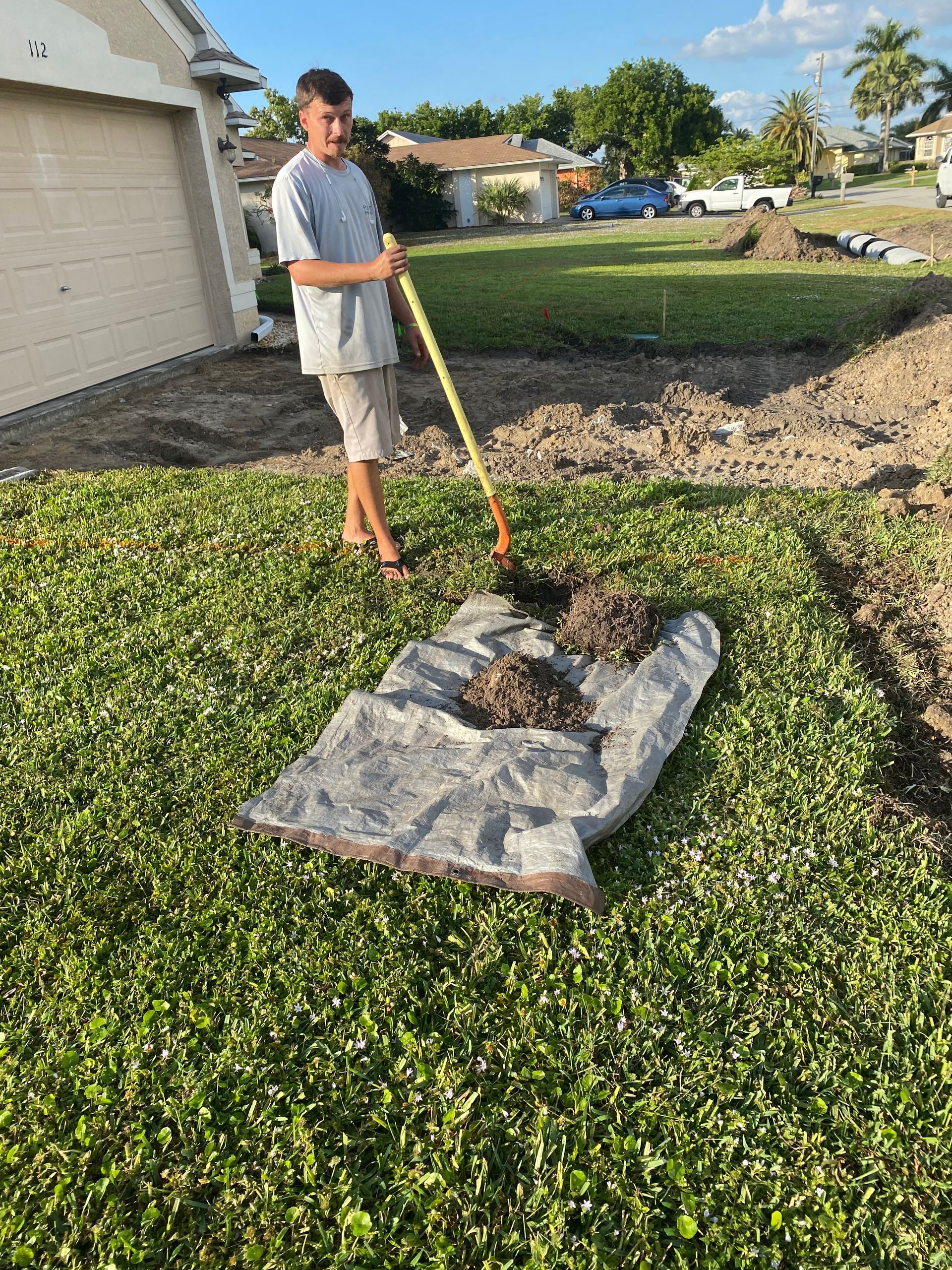 A man is standing in the grass holding a rake.