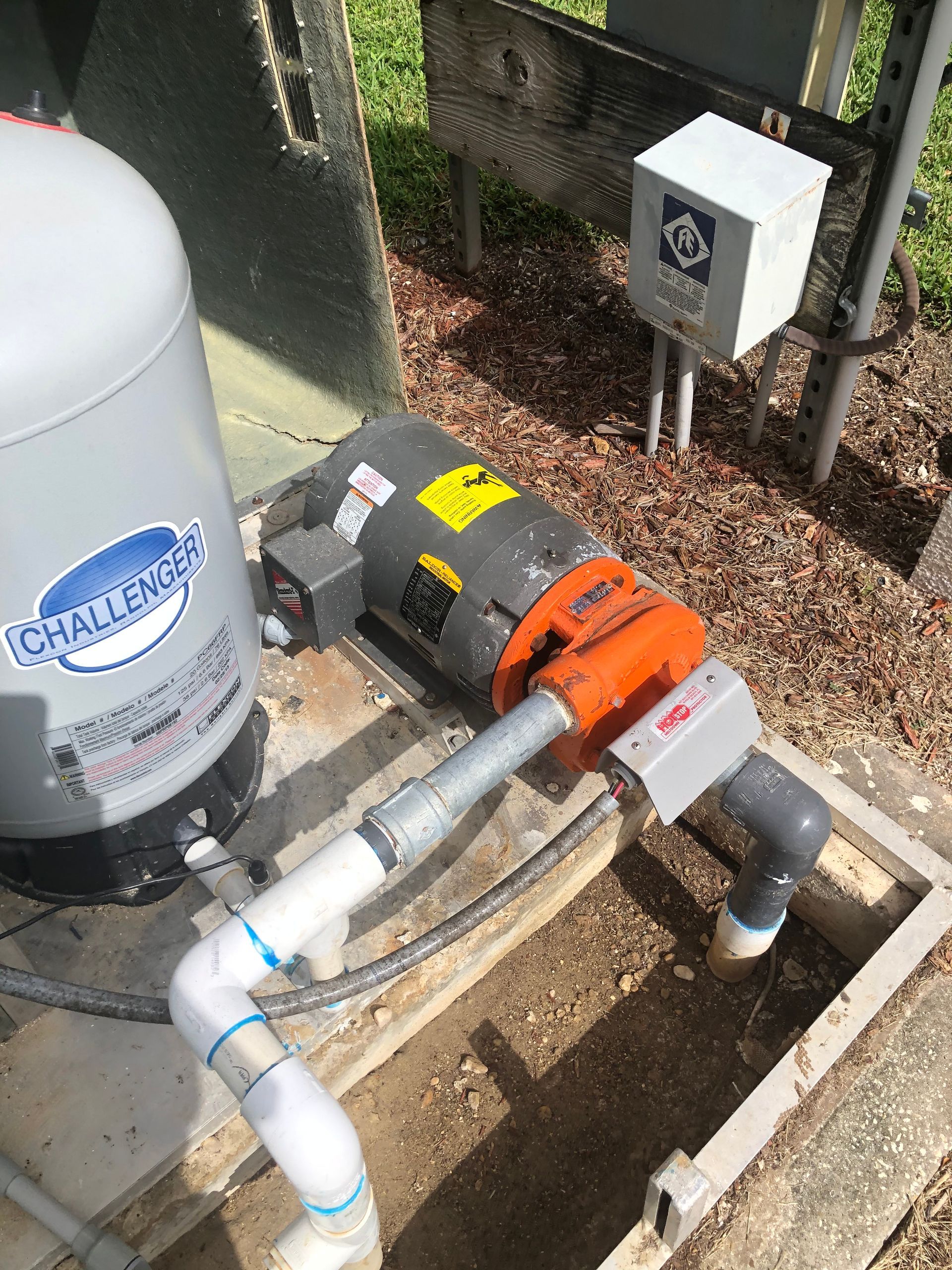 A water pump with a motor attached to it is sitting in the dirt.