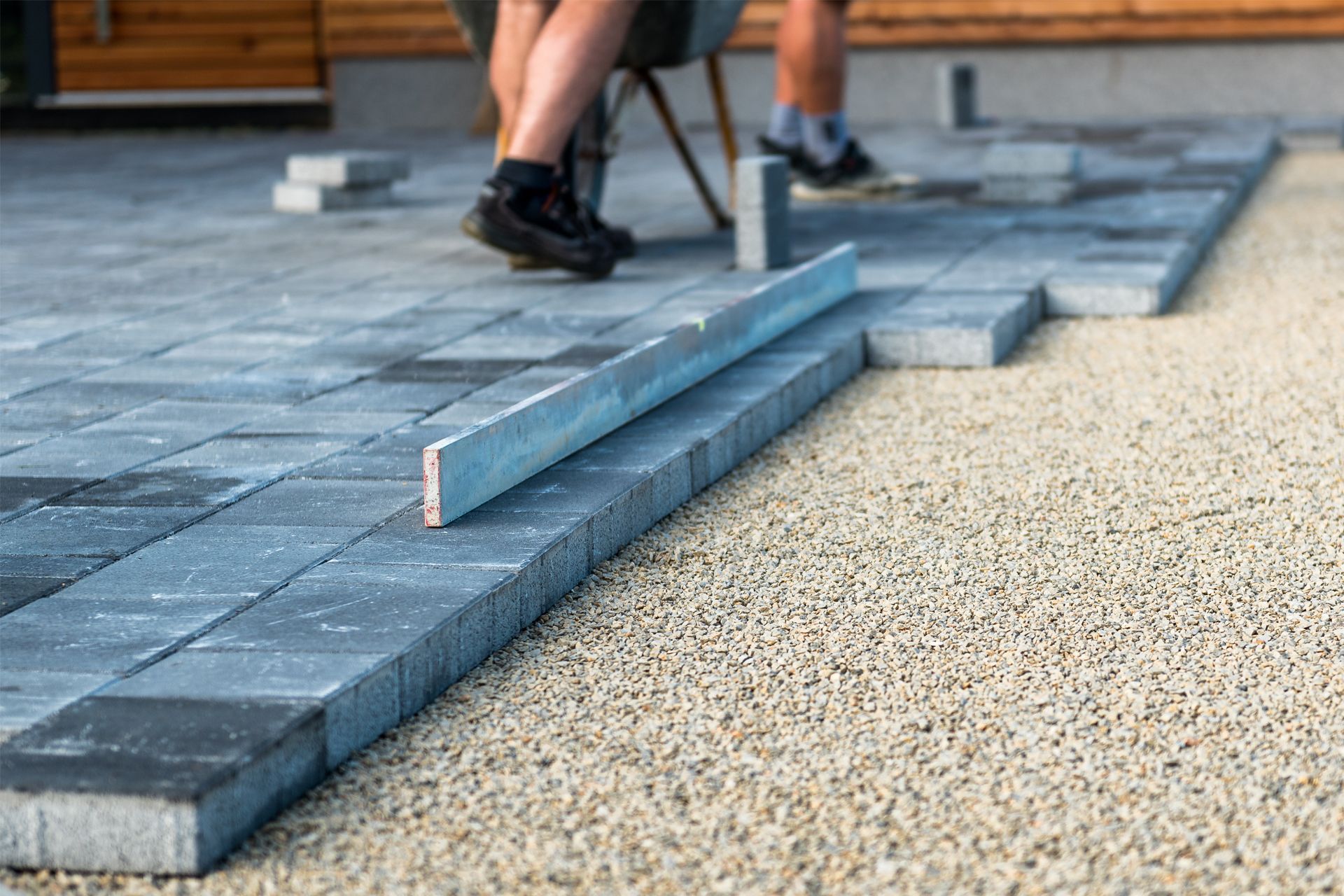 A person is laying concrete bricks on a patio with a level