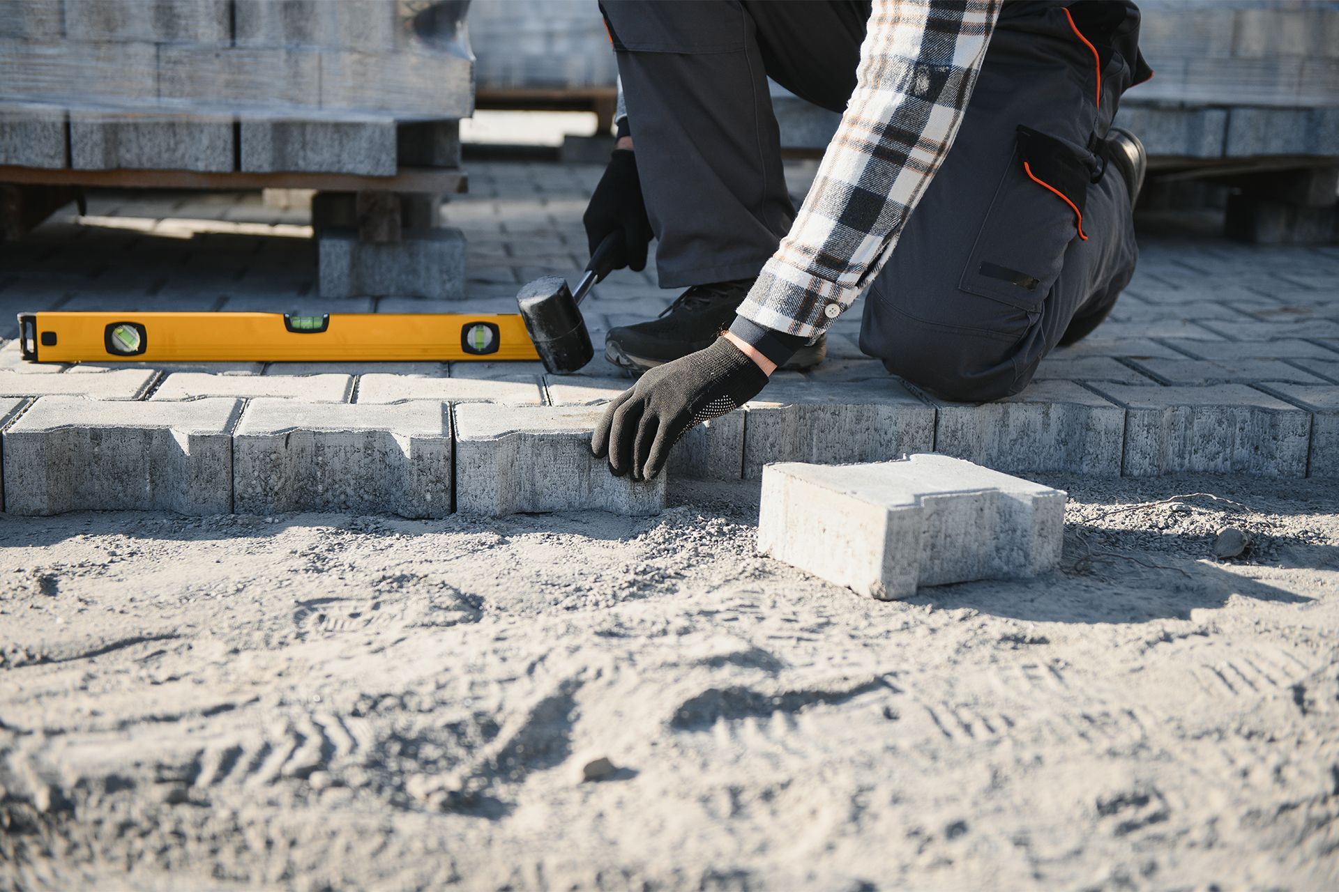 A man is laying bricks on a sidewalk