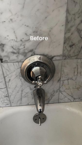 Before: Tub faucet with cross handle, chrome finish, set against marble wall above a white tub.