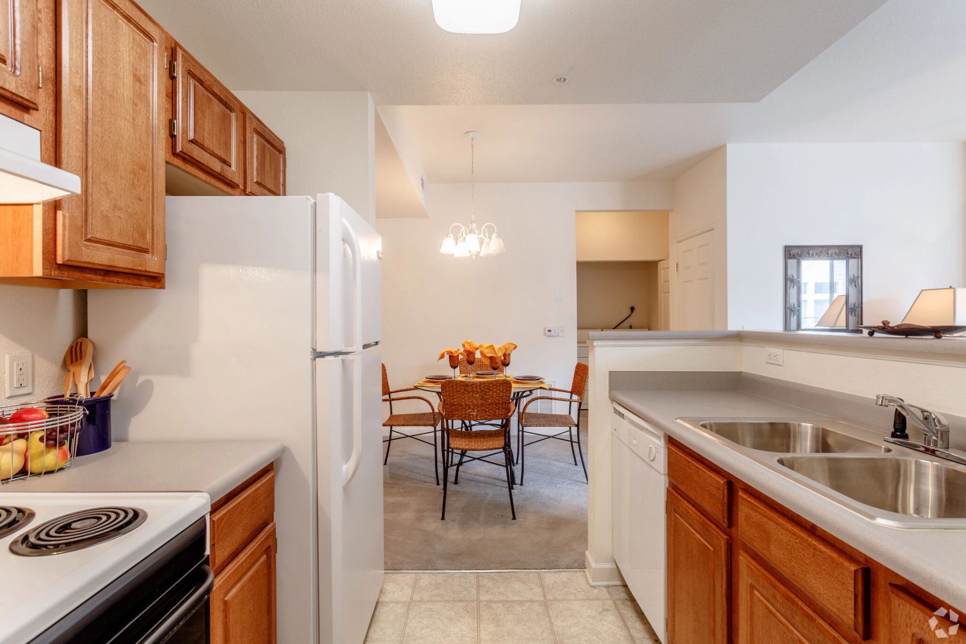 Bright kitchen with white appliances, wooden cabinets, and a dining area in the background