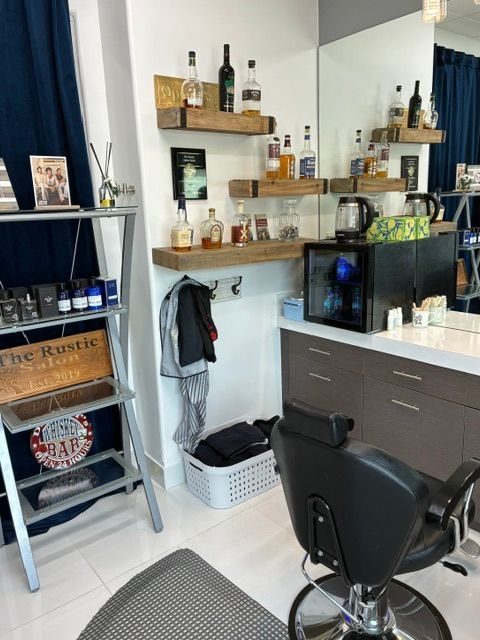 A barbershop interior featuring shelves with liquor bottles, a salon chair, a mirror, and a shelving unit with products.