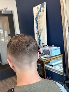 The back of a head showing a short, faded haircut with longer hair on top in a salon setting.