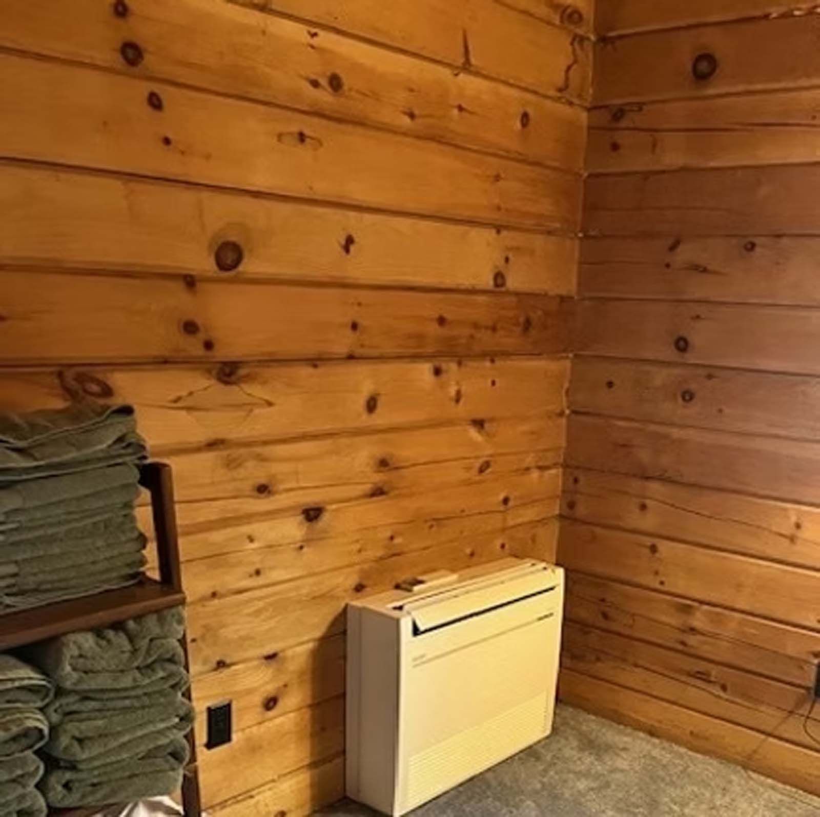 A room with wood paneling and a stack of towels on a shelf.