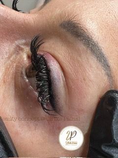 Nahaufnahme eines geschlossenen Auges mit langen, geschwungenen künstlichen Wimpern und geformter Augenbraue.