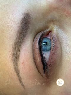 Nahaufnahme eines blauen Auges mit dunklem Make-up und geformter Augenbraue.