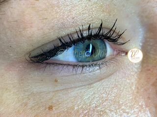 Nahaufnahme eines blauen Auges mit langem schwarzem Lidstrich und Mascara, die die Augenbraue und die umgebende Haut zeigt.