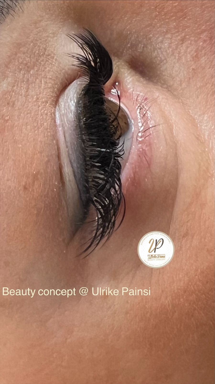 Nahaufnahme eines Auges mit dramatisch langen Wimpern und glänzendem Lidschatten in warmen Brauntönen