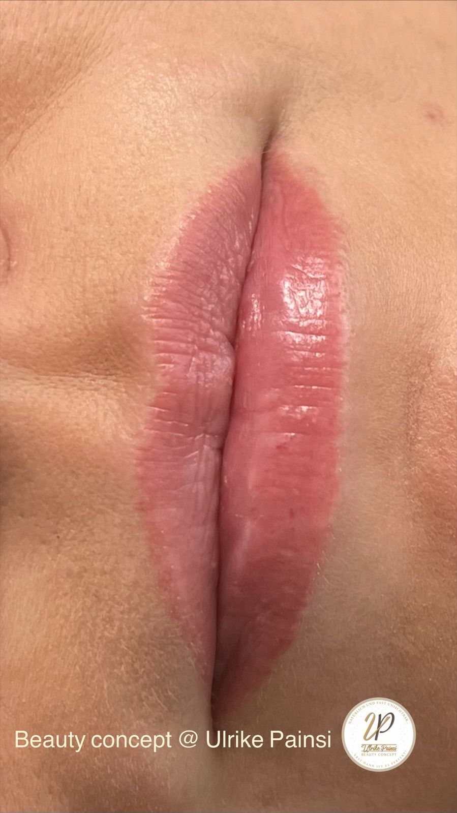 Nahaufnahme von glänzenden, leicht geöffneten, rosafarbenen Lippen vor hautfarbenem Hintergrund
