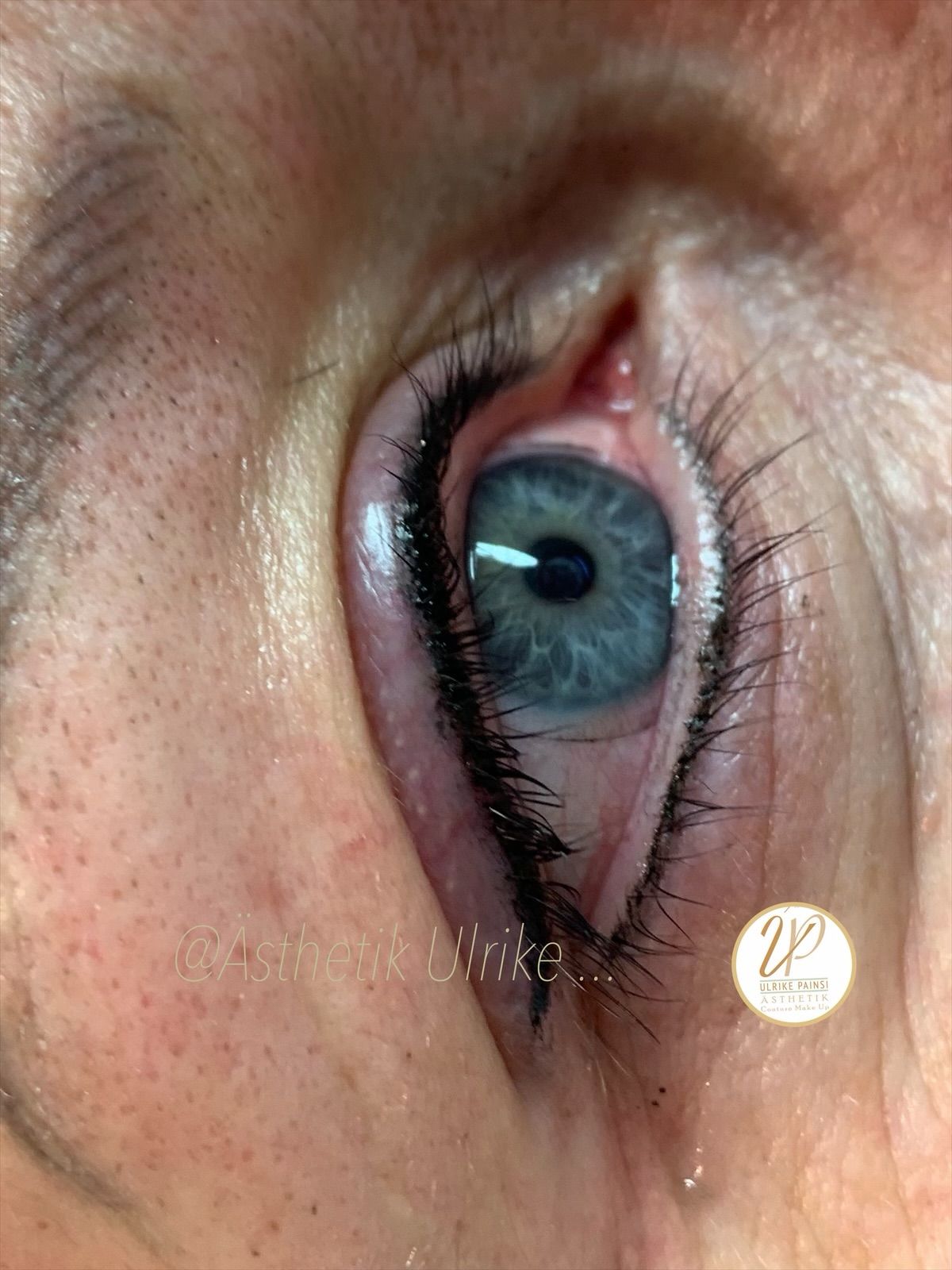 Nahaufnahme eines blauen Auges mit Make-up, das zur Seite blickt.