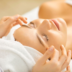 Gesichtsmassage im Spa-Stil, bei der eine Frau in ein weißes Handtuch gehüllt liegt, 