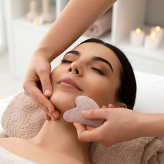 Gesichtsmassage im Spa mit Rosenquarz-Gua-Sha bei einem liegenden Kunden