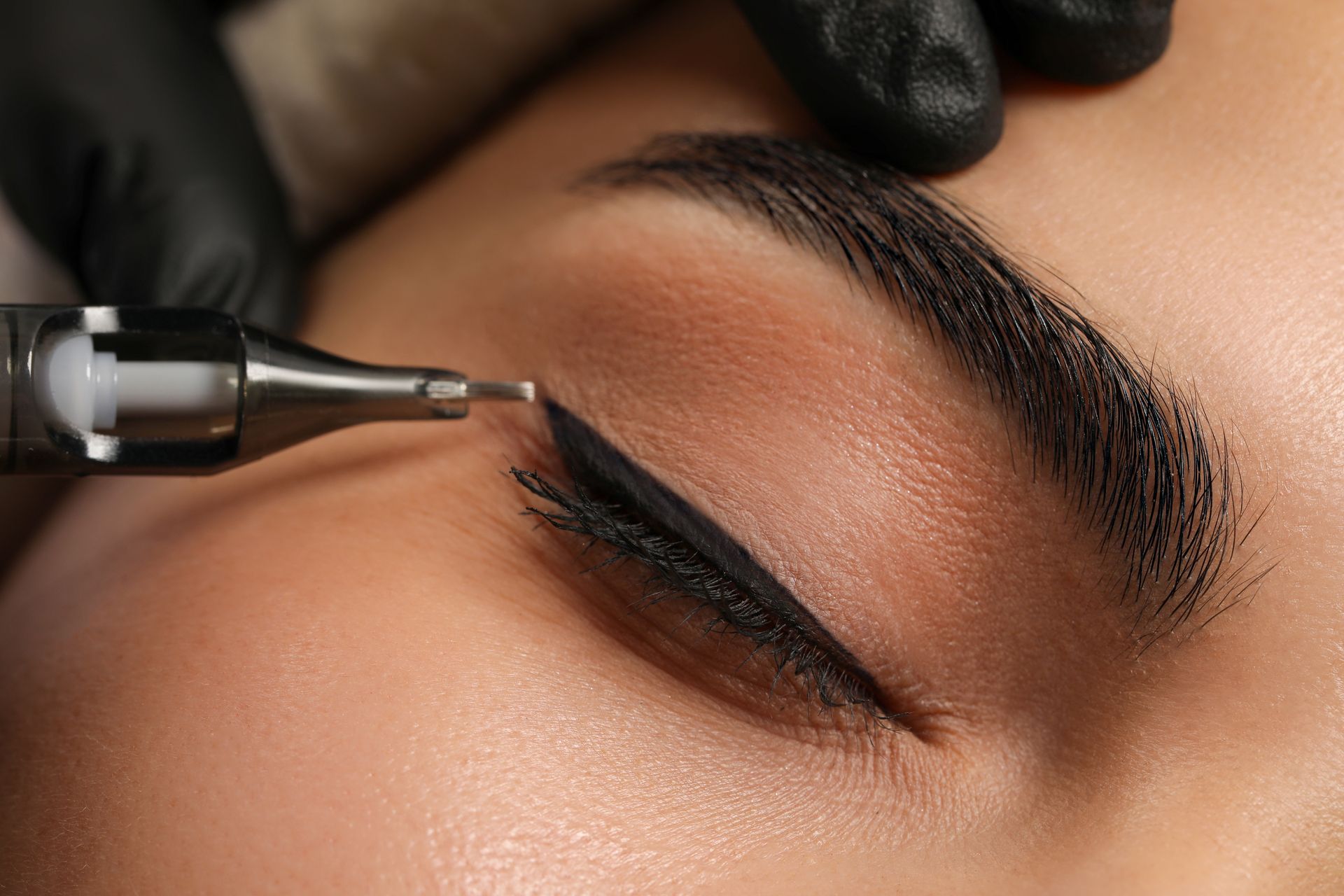 Nahaufnahme eines kosmetischen Tattoo-Stifts beim Auftragen von Eyeliner 