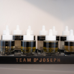 Eine Reihe kleiner Tropffläschchen auf einem Regal mit der Aufschrift „TEAM D'JOSEPH“