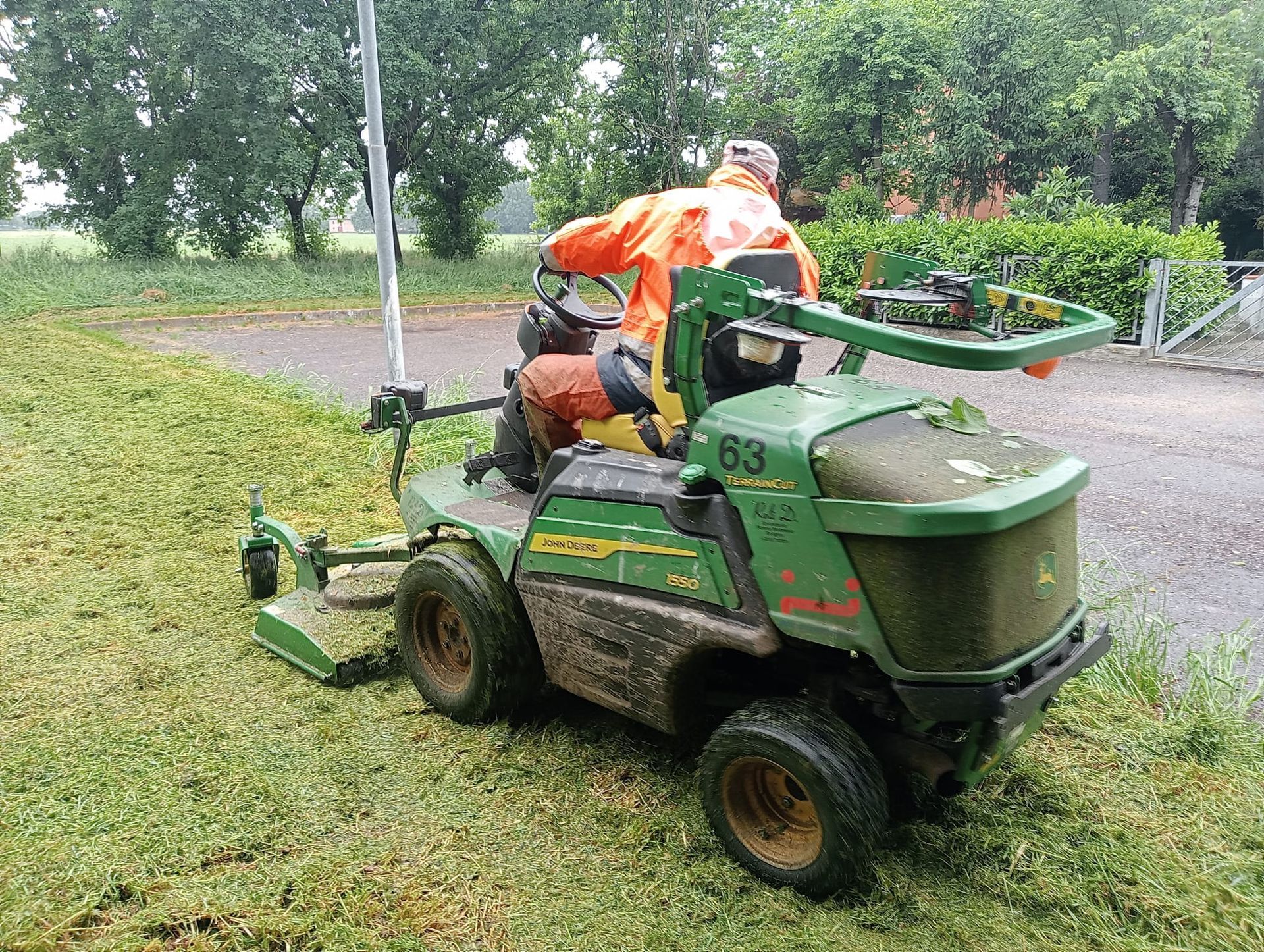 Una persona utilizza un tosaerba John Deere verde, tagliando l'erba in un campo all'aperto.