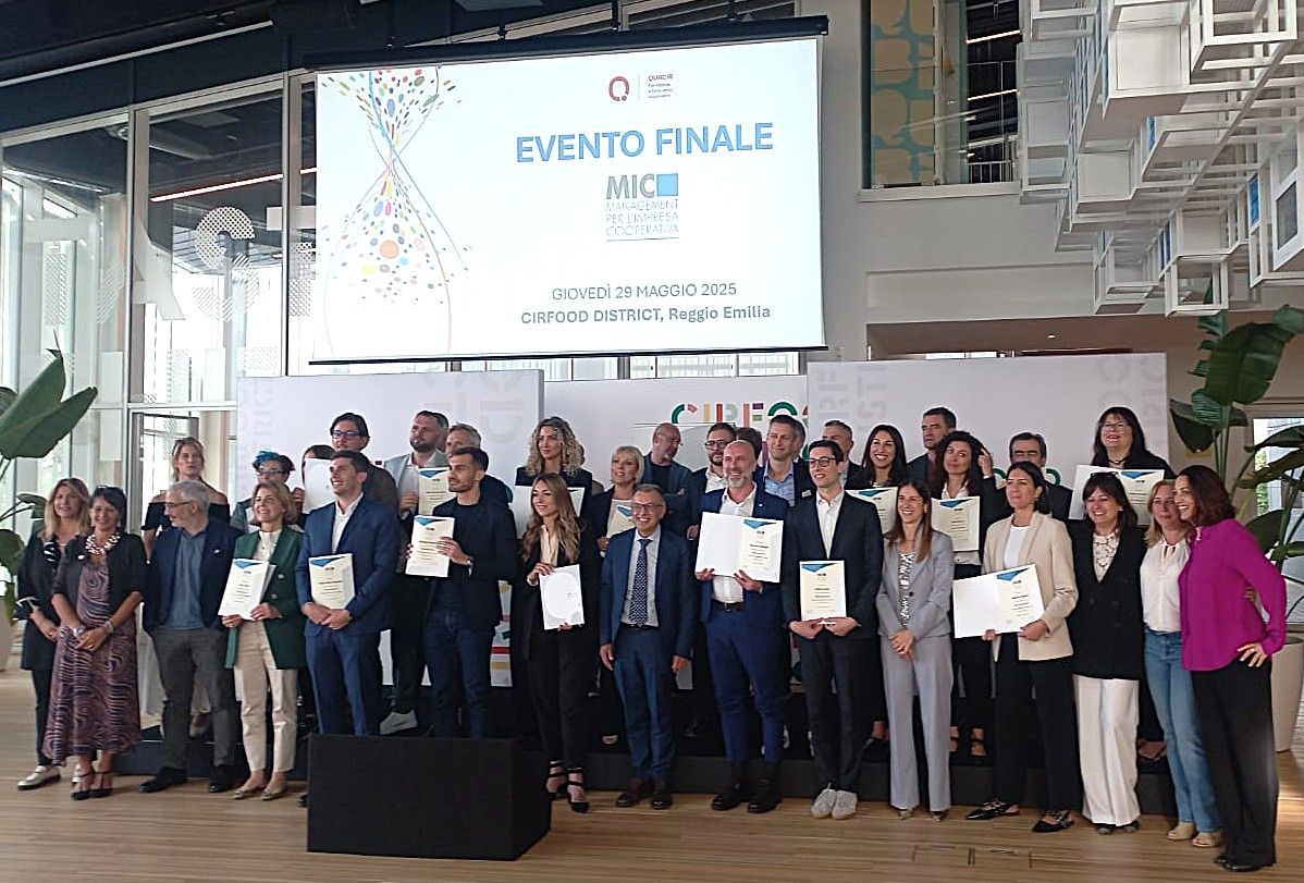 Gruppo di persone con certificati in mano, in posa davanti a uno striscione durante un evento.