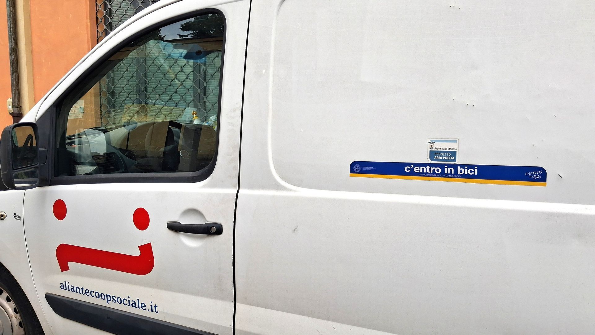 Furgone bianco con logo rosso e testo blu sul lato.
