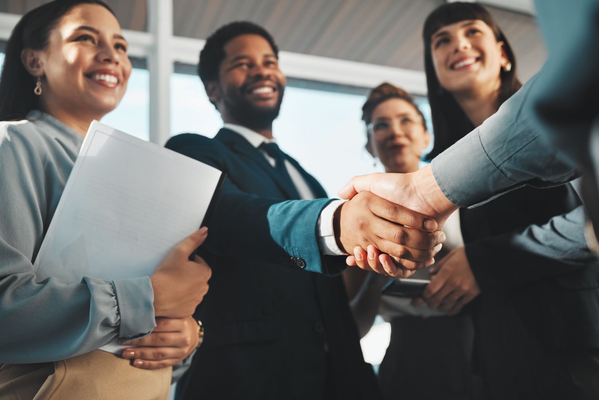 A group of business people are shaking hands in an office.
